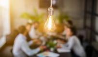 lightbulb in front of out of focus group of people at table